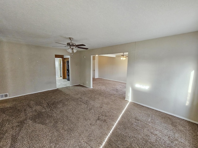 carpeted empty room with visible vents, a textured ceiling, and a ceiling fan