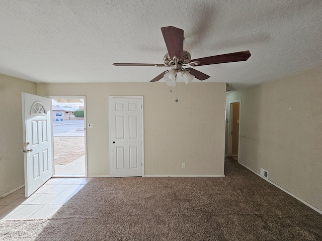 carpeted empty room featuring visible vents, a textured ceiling, and baseboards