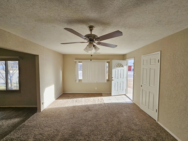 carpeted spare room with a wealth of natural light and a textured wall