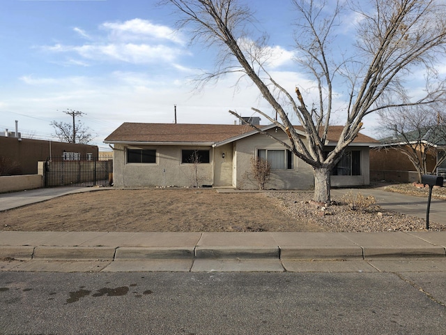 view of front facade with concrete driveway, fence, and stucco siding