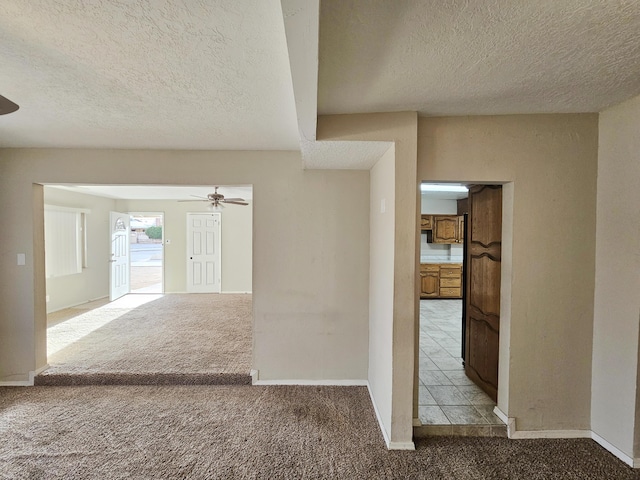 corridor featuring carpet flooring, a textured ceiling, and baseboards