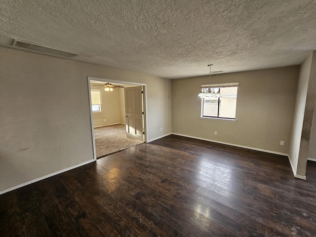 spare room featuring visible vents, dark wood-type flooring, a textured ceiling, baseboards, and ceiling fan