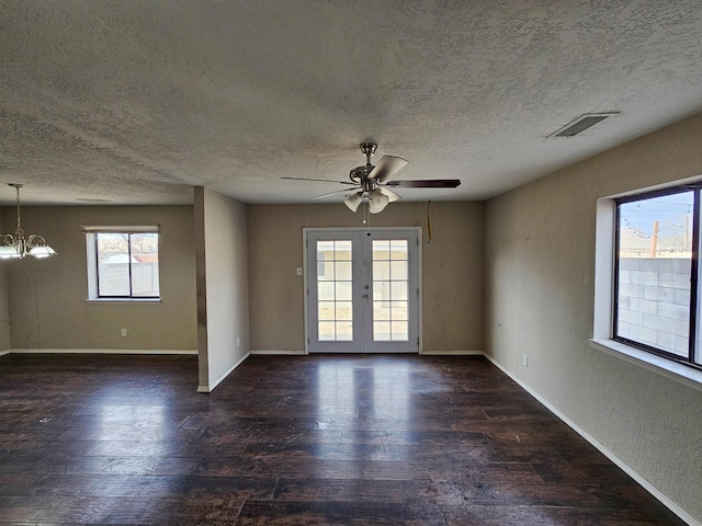 unfurnished room with visible vents, ceiling fan with notable chandelier, wood finished floors, french doors, and baseboards