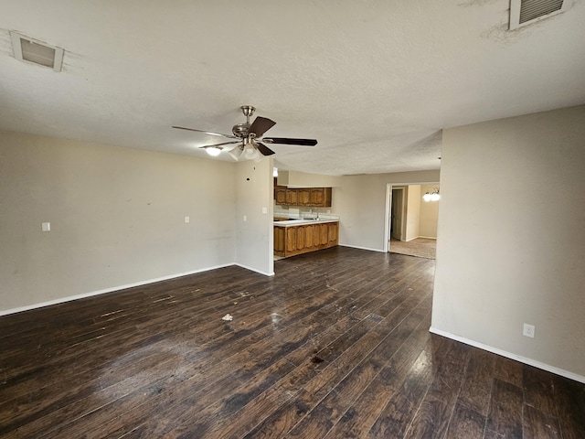 unfurnished living room with visible vents, a textured ceiling, dark wood-style floors, and ceiling fan with notable chandelier