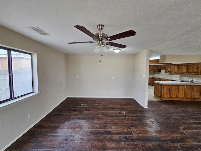 unfurnished living room featuring a sink, visible vents, dark wood-type flooring, and a textured ceiling