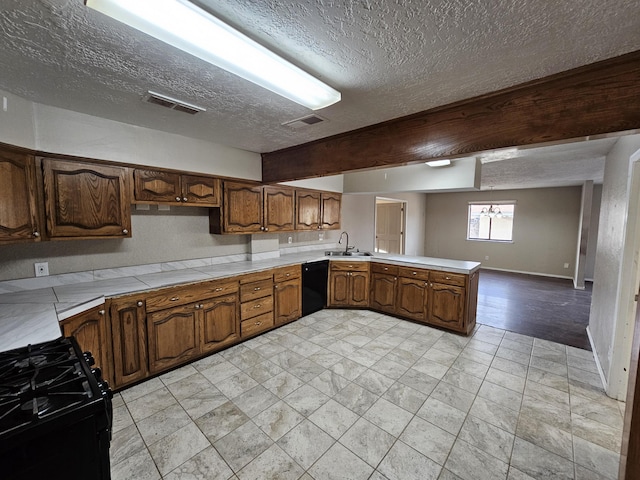 kitchen with visible vents, black appliances, a sink, a peninsula, and light countertops