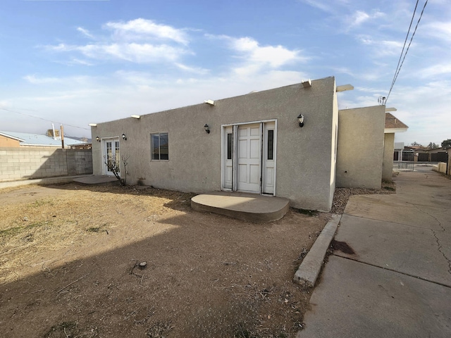 back of property featuring stucco siding and fence