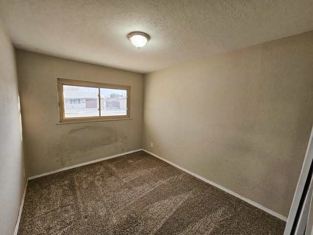 unfurnished room with baseboards, dark carpet, and a textured ceiling