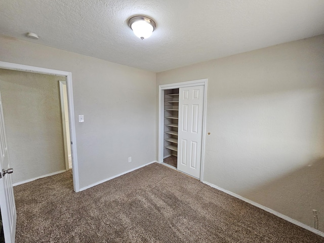 unfurnished bedroom with baseboards, a closet, carpet floors, and a textured ceiling