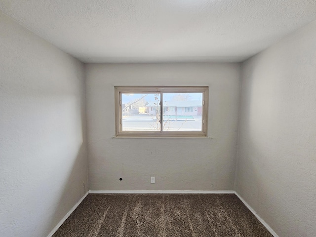 carpeted spare room with baseboards and a textured ceiling