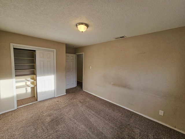 unfurnished bedroom featuring visible vents, a textured ceiling, a closet, carpet flooring, and baseboards