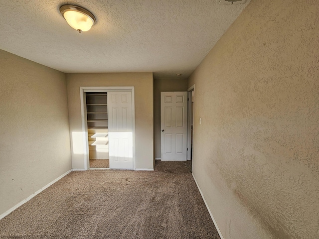 unfurnished bedroom with carpet flooring, a textured wall, a closet, and baseboards