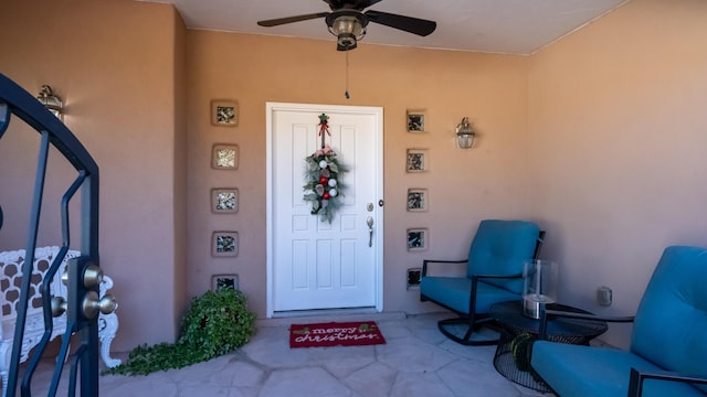 entrance to property featuring ceiling fan and stucco siding