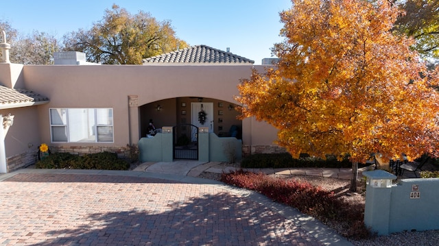 view of front of home with stone siding, a tile roof, and stucco siding