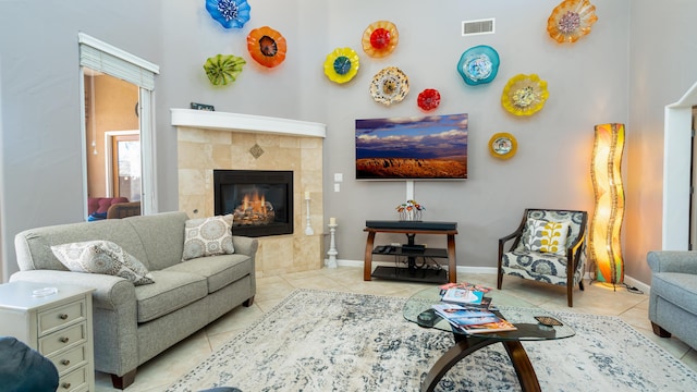 living room featuring tile patterned flooring, a fireplace, visible vents, and baseboards