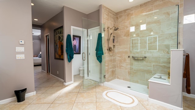 bathroom with ensuite bathroom, toilet, baseboards, a shower stall, and tile patterned floors