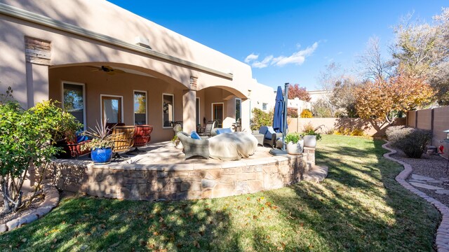 rear view of property with a lawn, a patio, ceiling fan, fence, and stucco siding