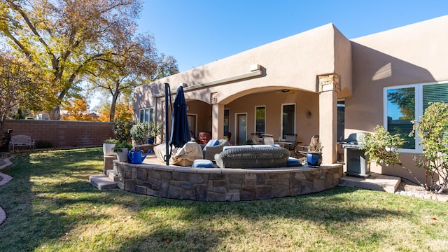 back of property with a patio area, stucco siding, a lawn, and fence