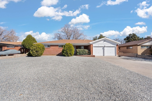 single story home featuring an attached garage, brick siding, and driveway