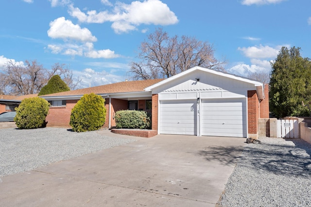 ranch-style home with brick siding, an attached garage, driveway, and a gate