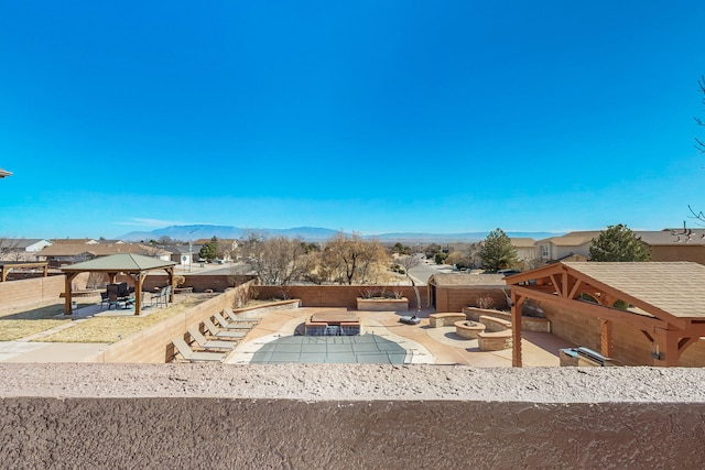 exterior space with a fire pit, a fenced backyard, a gazebo, a patio area, and a mountain view