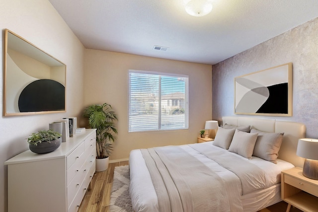 bedroom with light wood finished floors, baseboards, and visible vents