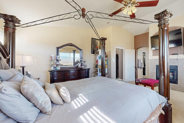 bedroom featuring arched walkways, a fireplace, tile walls, lofted ceiling, and carpet flooring