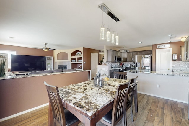 dining area with recessed lighting, light wood-style flooring, ceiling fan, a tile fireplace, and baseboards