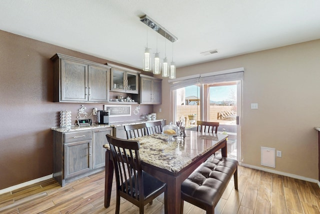 dining space featuring light wood-style floors, baseboards, and visible vents