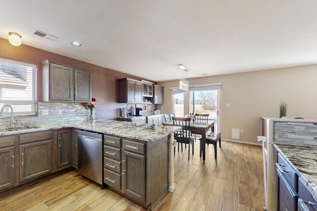 kitchen featuring light wood-style flooring, a sink, visible vents, backsplash, and dishwasher