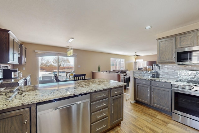 kitchen featuring appliances with stainless steel finishes, a healthy amount of sunlight, backsplash, and light wood finished floors