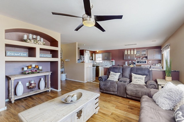 living room featuring a ceiling fan, light wood-type flooring, and baseboards