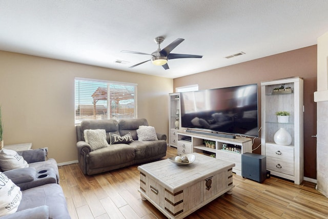 living room with baseboards, wood finished floors, visible vents, and a ceiling fan