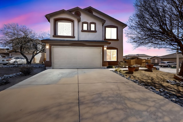 view of front of home featuring a garage, concrete driveway, and stucco siding