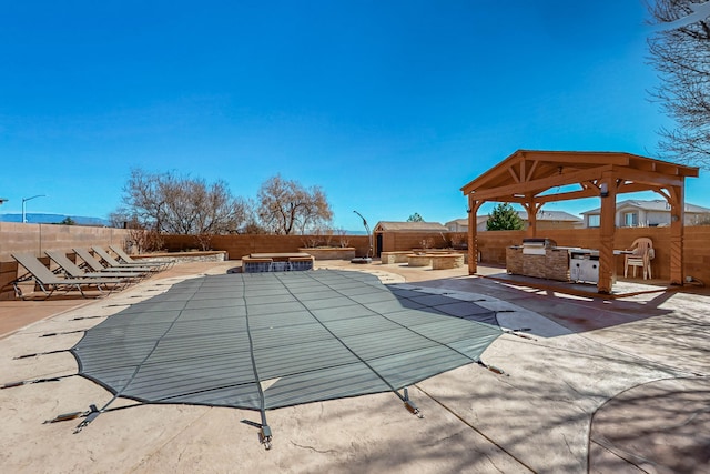 pool featuring a gazebo, a patio area, a fenced backyard, and an outdoor kitchen