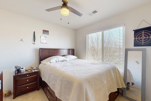 bedroom with visible vents, a ceiling fan, and light colored carpet