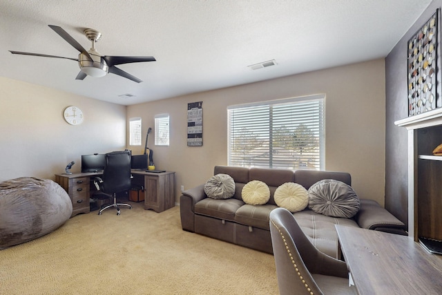 office area featuring light colored carpet, visible vents, ceiling fan, and a textured ceiling