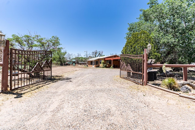 view of street featuring gravel driveway, a gate, and a gated entry