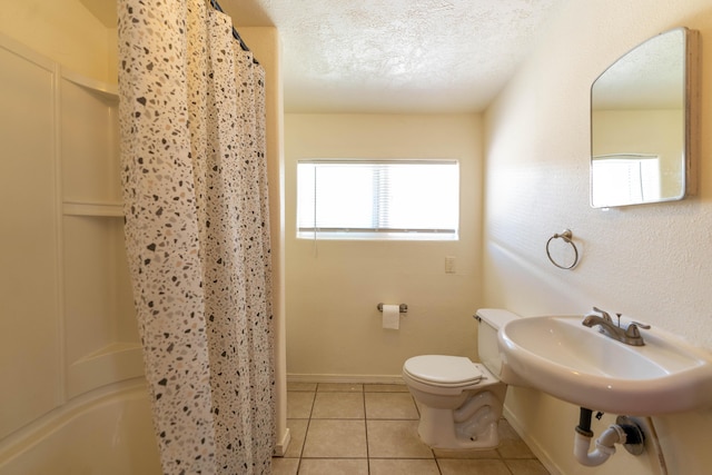 bathroom featuring baseboards, toilet, tile patterned flooring, shower / bath combo with shower curtain, and a textured ceiling