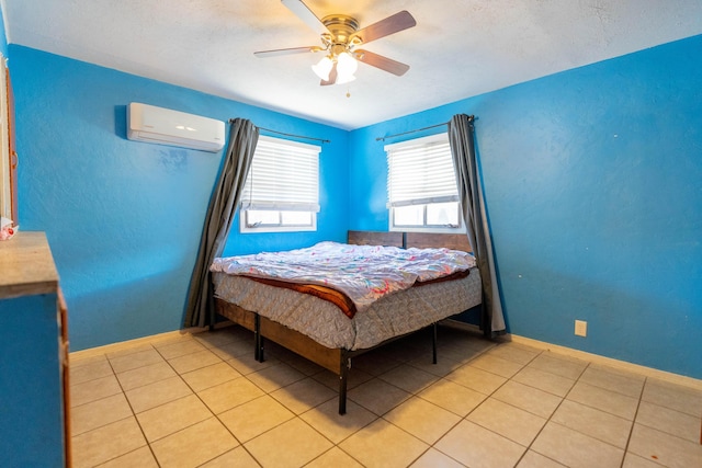 bedroom featuring an AC wall unit, ceiling fan, baseboards, and light tile patterned floors