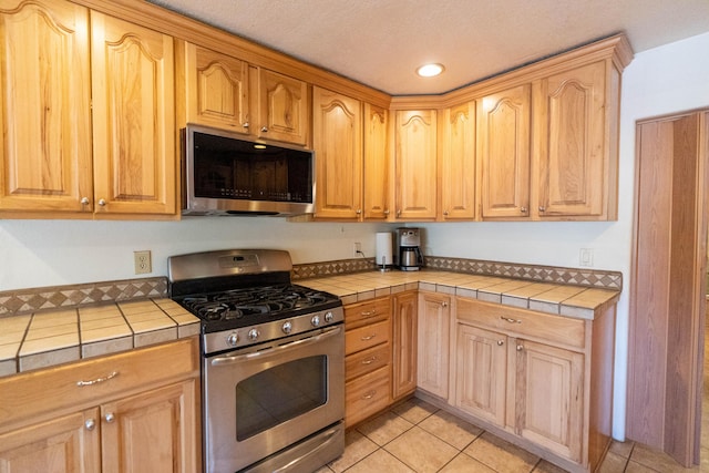 kitchen featuring tile countertops, light tile patterned floors, and appliances with stainless steel finishes