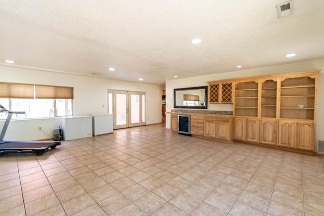 unfurnished living room featuring wine cooler, french doors, visible vents, and recessed lighting