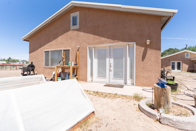 rear view of property featuring stucco siding, a patio area, and french doors