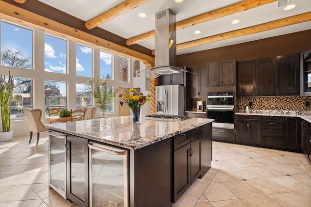 kitchen with decorative backsplash, wine cooler, appliances with stainless steel finishes, light stone counters, and island exhaust hood