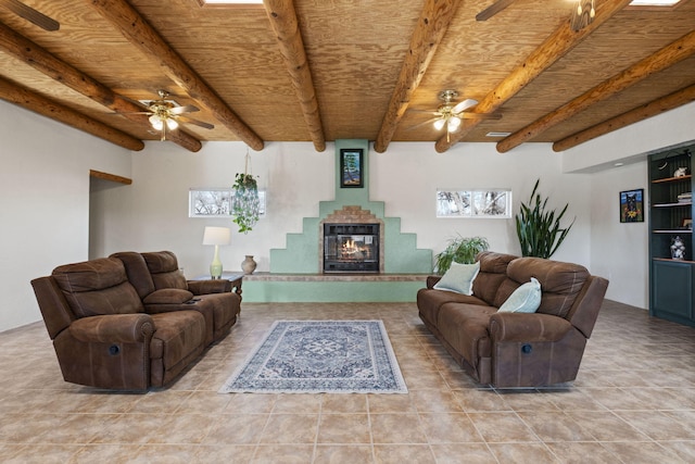 living room with ceiling fan, beamed ceiling, wooden ceiling, and a glass covered fireplace