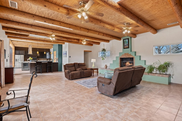 living area with a tiled fireplace, beam ceiling, wooden ceiling, and visible vents