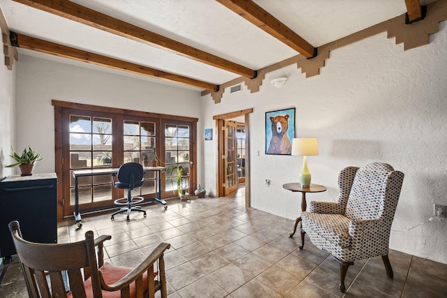 interior space featuring tile patterned flooring, visible vents, beam ceiling, and a textured wall