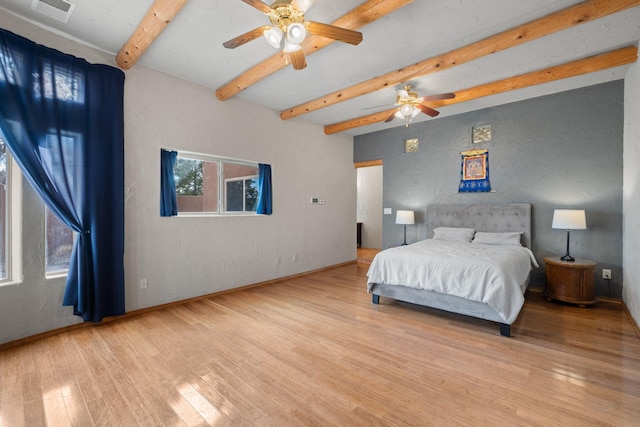 bedroom featuring baseboards, visible vents, a textured wall, wood finished floors, and beamed ceiling