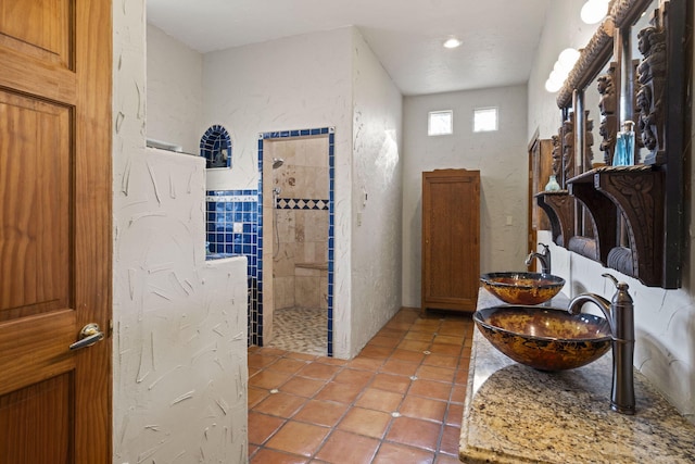 interior space featuring tile patterned flooring, double vanity, a sink, and walk in shower