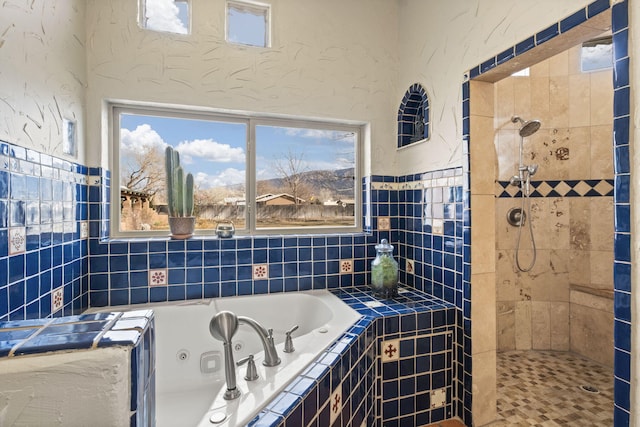 full bath featuring a whirlpool tub, tiled shower, and a textured wall